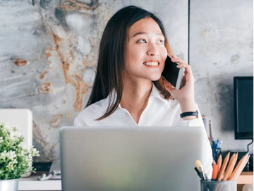 A woman sitting at her desk talking on the phone.